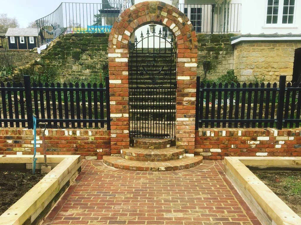 Reclaimed brick archway with wrought iron gate, built by Waller & Smith in Godalming
